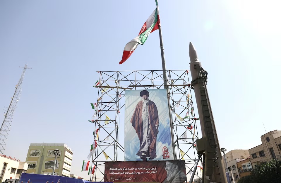 Sebuah sistem rudal Iran dipamerkan di samping spanduk dengan gambar Pemimpin Tertinggi Iran, Ayatollah Ali Khamenei, dan mendiang pemimpin Hezbollah Lebanon, Hassan Nasrallah, di sebuah jalan di Teheran, Iran, pada 2 Oktober 2024. Majid Asgaripour/WANA (West Asia News Agency) via REUTERS.